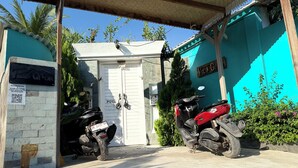 A gated entrance with a white door, two motorcycles parked outside, and a sign indicating accommodation availability. - Villa giyor (Lembongan Island)