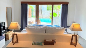 A hotel room with a bed, two bedside lamps, a large mirror, and a view of an outdoor swimming pool. - Villa giyor (Lembongan Island)