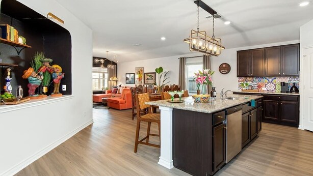 Una cocina moderna con armarios oscuros, una isla central y una zona de comedor con un sofá rojo.