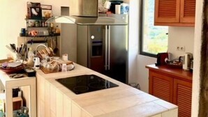 Une cuisine moderne dotée d’un îlot central, d’appareils électroménagers en acier inoxydable et d’armoires en bois.