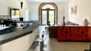 Une cuisine moderne avec un long comptoir, une arche en pierre et un meuble rouge.