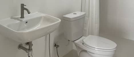 Un baño moderno con lavamanos, inodoro y ducha.