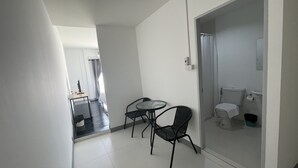 Habitación de hotel con una mesita, dos sillas, ducha y váter.