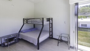 Habitació amb literes, escriptori, taula petita i finestra amb vistes a l'exterior.