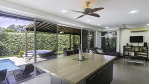 Una cuina moderna amb una illa gran, zona de menjador amb seients exteriors i piscina.