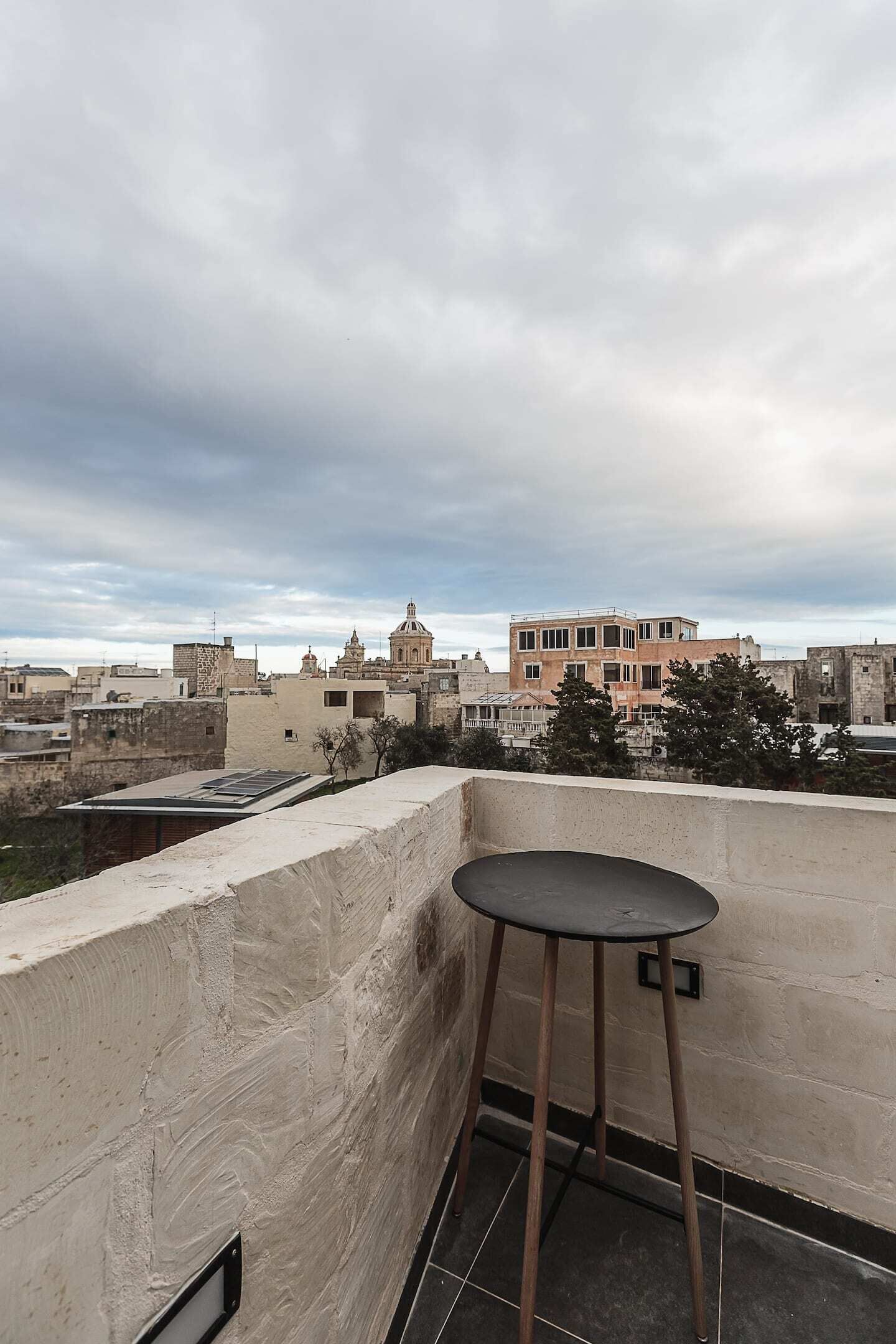 A rooftop terrace with a single table and a view of a cityscape including historic buildings.