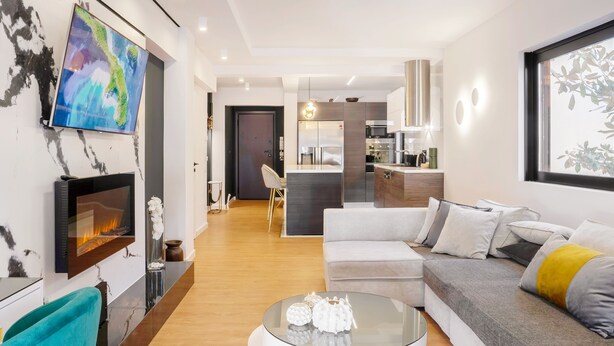 Ein modernes Wohnzimmer mit Kamin, einer Couch, einem Couchtisch und einem an der Wand befestigten Fernseher.
