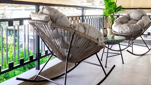 Ein Balkon mit Korbstühlen, einem Blumentopf und einem gefliesten Boden.