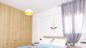 Un dormitorio con cama, armario de madera, mesita de noche y un adorno colgante.