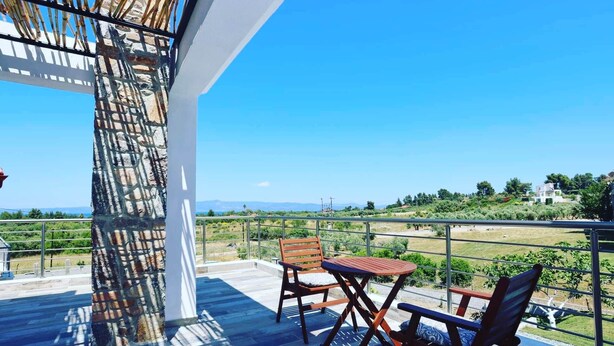 Un balcón con vista a un paisaje rural, que incluye una mesa y dos sillas.