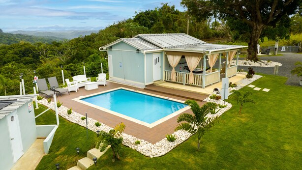 A poolside area with a pool, lounge chairs, and a covered seating area.