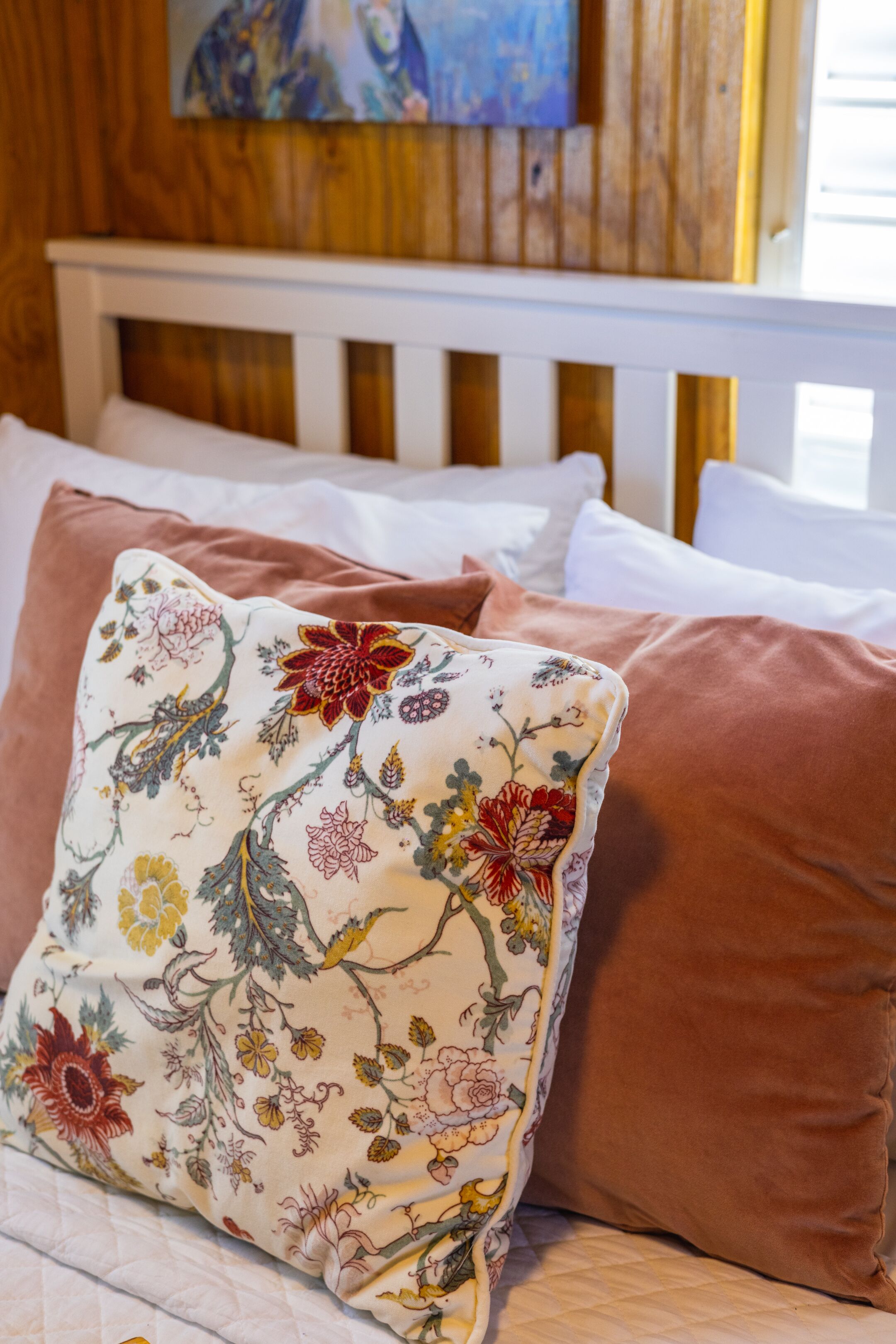 A bed with floral-patterned pillows and a wooden headboard.