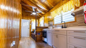 A wooden cabin interior with a kitchen area, including cabinets, a stove, and a sink.