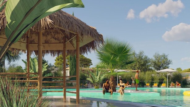Un área de piscina con una estructura de techo de paja, palmeras y sillones de descanso.