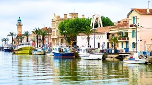 Un puerto con barcos amarrados, una torre destacada y edificios históricos con balcones.
