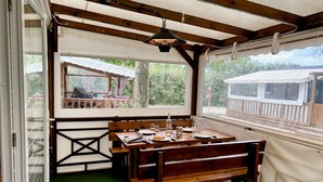 Un patio techado con una mesa de madera lista para comer, una banca y vistas al exterior.