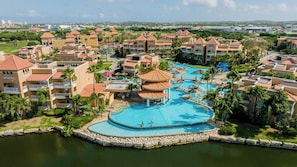 Ein Resort mit mehreren Gebäuden, einem zentral gelegenen Pool und einer umlaufenden Wasserfläche.