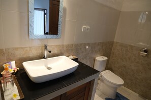 A bathroom with a white sink, a mirror, a toilet, and a towel rack.