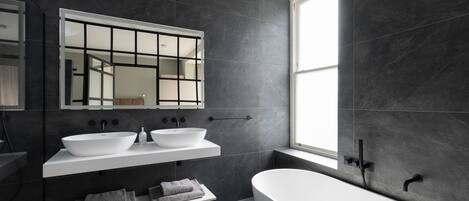 A modern bathroom with a freestanding bathtub, a large mirror, and a double sink vanity.