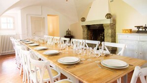 A long dining table set with white chairs, a stone fireplace, and a white door.