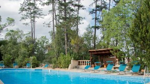 A swimming pool with lounge chairs and a gazebo, surrounded by trees.