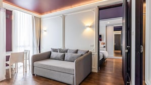 Un salon moderne avec un canapé gris, un plancher en bois et une grande fenêtre agrémentée de rideaux.