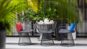 Un espace extérieur moderne aménagé avec trois chaises, une table et un pot de fleurs.