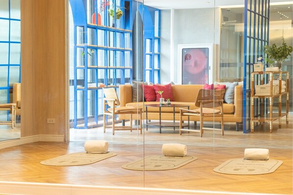 A modern hotel lobby with a sofa, chairs, a coffee table, and a glass partition. - Blue Hippo Hotel (Samut Prakan)