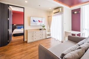 Una habitación de hotel moderna con cama, sofá, escritorio y televisión.