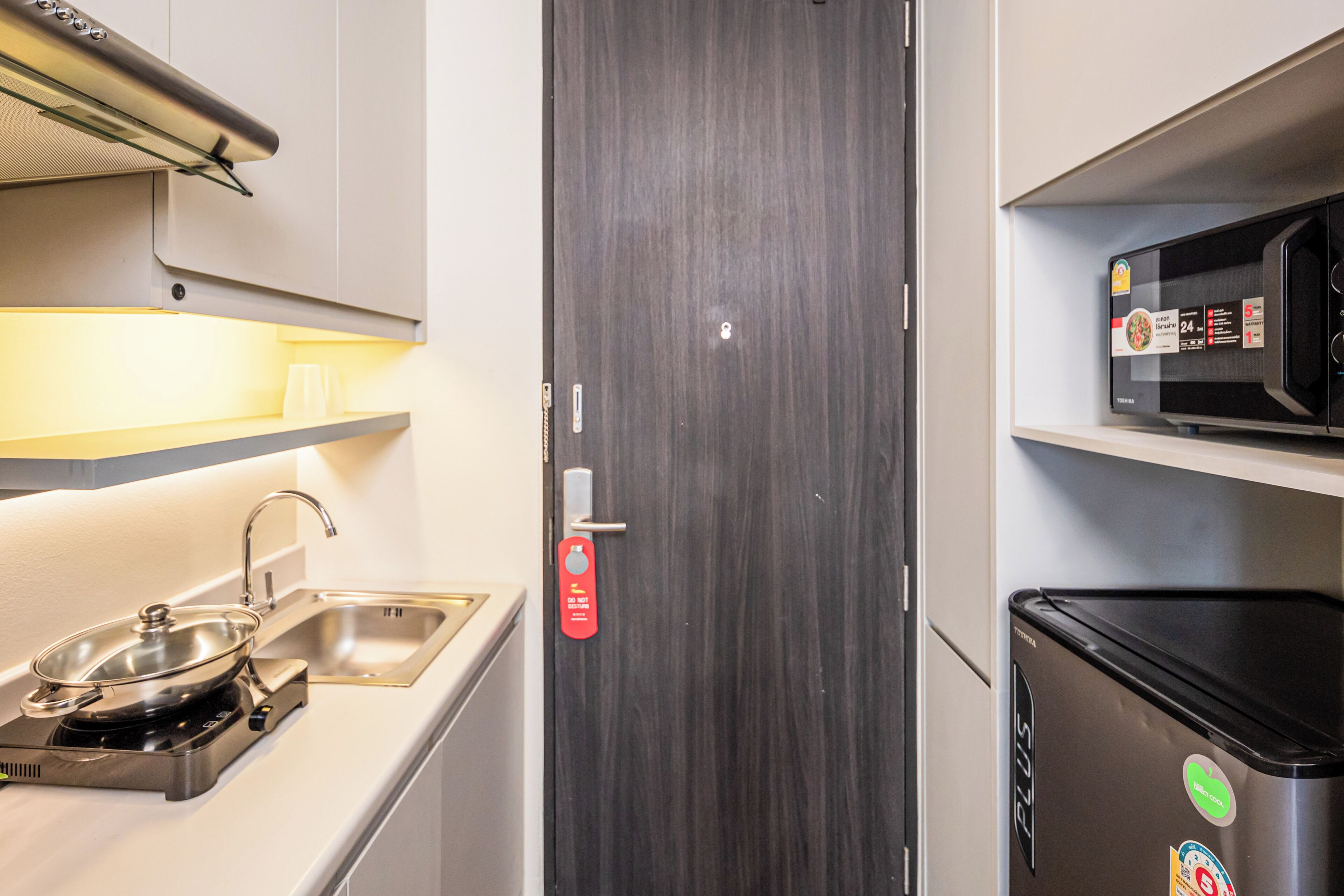 A compact kitchenette with a stove, sink, and microwave.