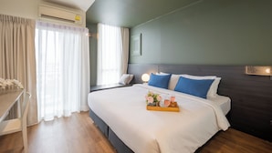Une chambre d’hôtel avec un grand lit, une table de chevet et une fenêtre avec des rideaux.