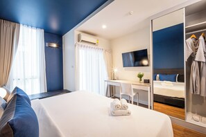 A hotel room with a bed, a desk, a TV, and a wardrobe.