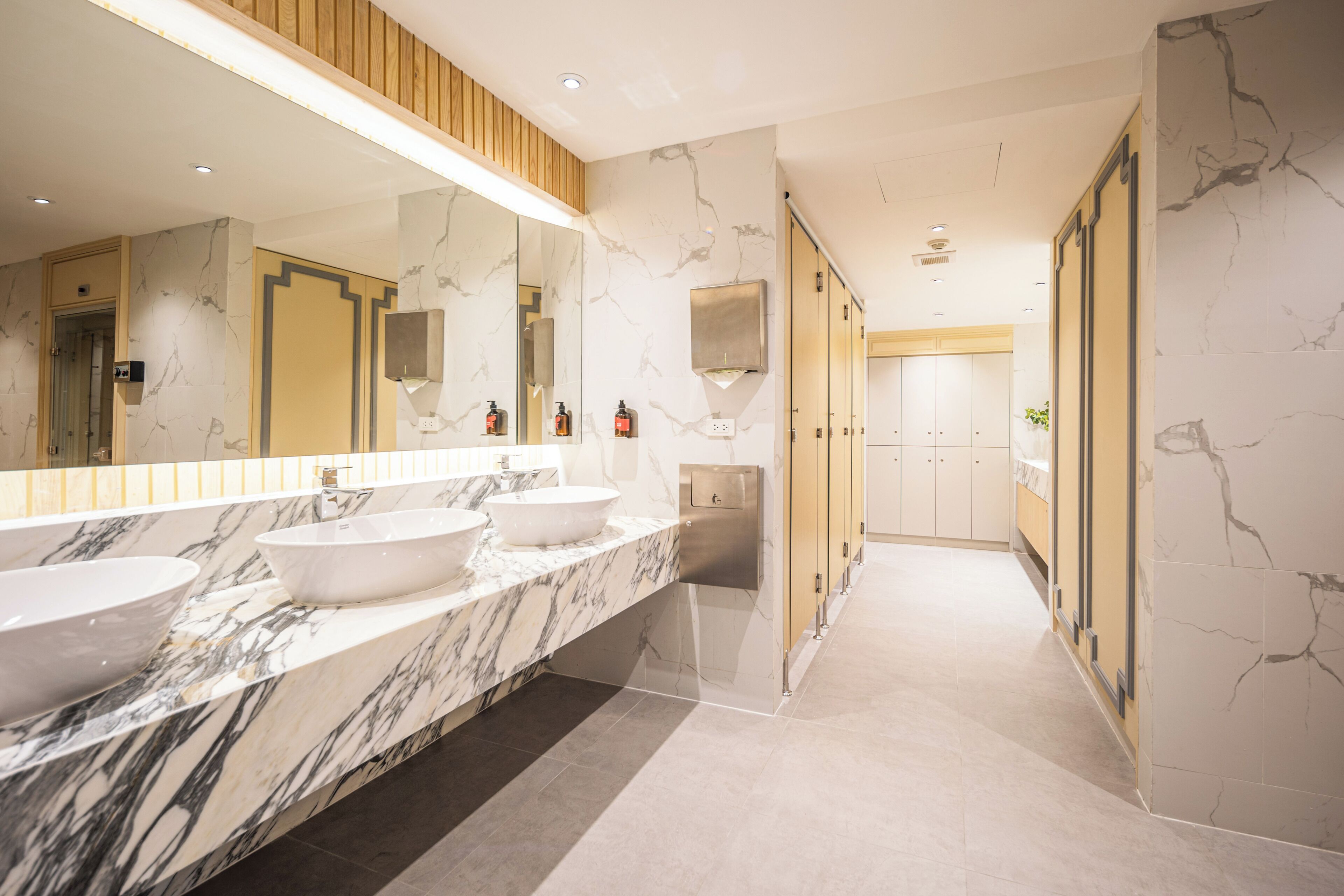 A modern bathroom with marble countertops, two sinks, a large mirror, and a walk-in shower.