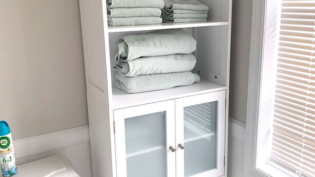A white cabinet with glass doors and shelves holding folded towels. - Cottage close to Seaside Heights beach, Parking (Seaside Heights)