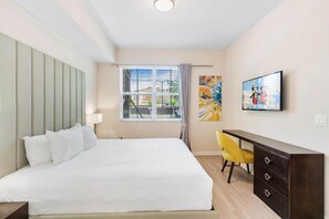 A bedroom with a bed, a desk, a chair, a TV, and a window with blinds. - Resort Condo: 3BR w Balcony & Parking near Disney! (Orlando)