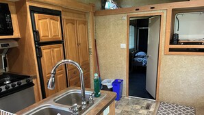 A compact kitchenette with a stove, sink, and wooden cabinets.