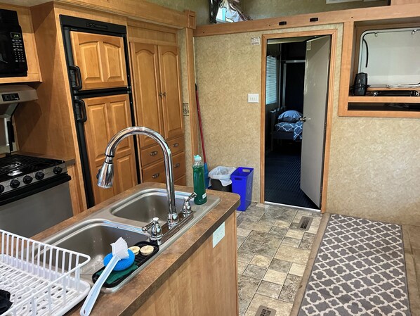 Una kitchenette compacta con estufa, lavamanos y armarios de madera.