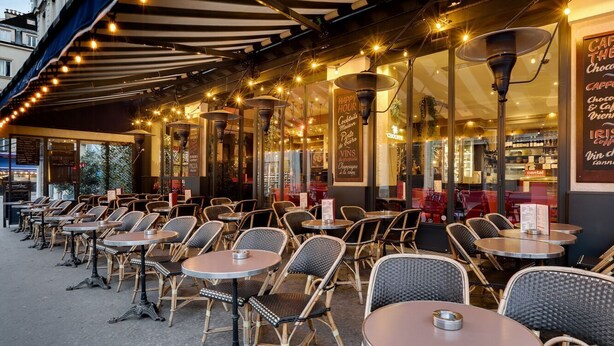 An outdoor cafe with tables and chairs, a menu board, and string lights. - Magnificent apartment between Paris and Disneyland. Rer A 10 min by bus -PARKING  (Neuilly-sur-Marne)