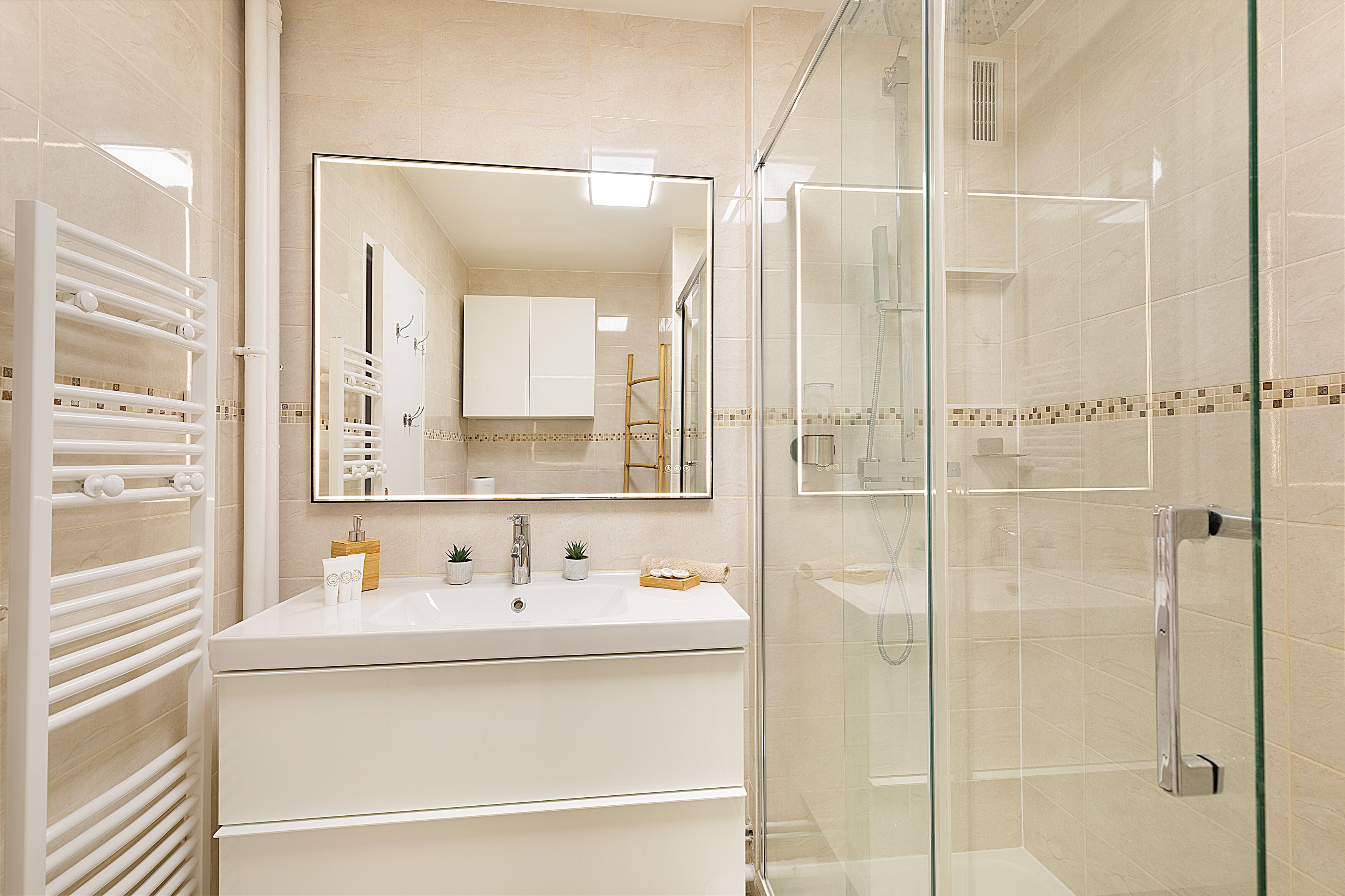 Une salle de bain moderne avec une douche à parois de verre, un meuble-lavabo blanc avec un miroir et un porte-serviettes.