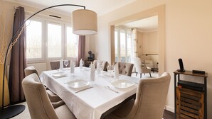 A dining area with a table set for four, including plates, glasses, and cutlery. There are chairs around the table, and a lamp is positioned above it. - Magnificent apartment between Paris and Disneyland. Rer A 10 min by bus -PARKING  (Neuilly-sur-Marne)