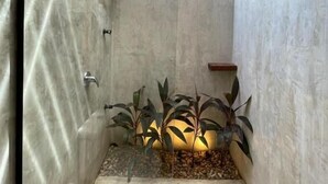 Un espace douche moderne avec une porte en verre, des poutres en bois et une petite composition florale.
