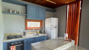 Une cuisine dotée d’un îlot central, de meubles bleus, d’un réfrigérateur blanc et d’un plafond en bois.