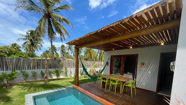 Un espace aménagé au bord de la piscine, avec une terrasse en bois, une table et des chaises, et un hamac.