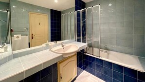 Un bagno con lavandino, specchio, cabina doccia e porta.