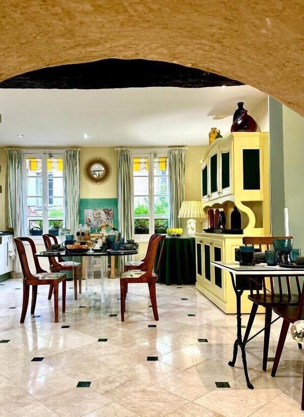 Un comedor amplio con techo alto, una mesa central con sillas y un armario amarillo con puertas de cristal.