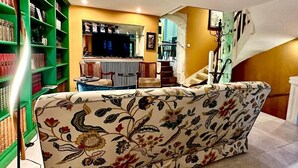 Un soggiorno con un divano, una libreria verde, un'area pranzo e una scala.