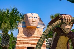 Een grote, piramidevormige structuur met een gezicht, omringd door palmbomen.