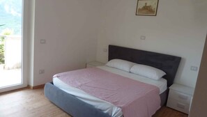 A bedroom with a bed, a nightstand, a dresser, and a window with a view. - Holiday apartment with terrace and parking (Tenno)