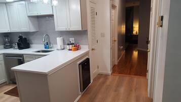 A modern kitchen with white cabinets, a central island, and a wooden floor.