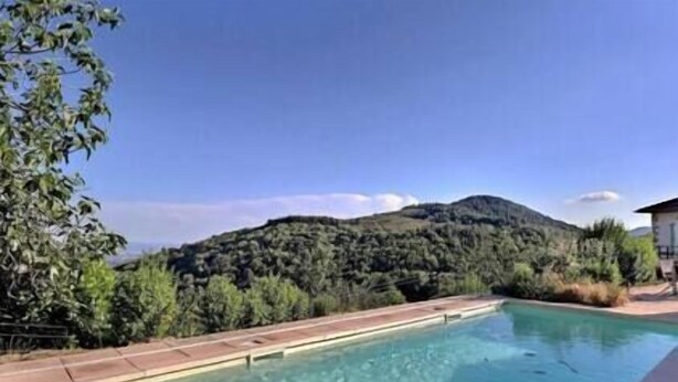 A swimming pool with a mountain backdrop, surrounded by greenery and a clear sky. - The Vault of the Stars overlooks the Monts d’Ardèche (Genestelle)